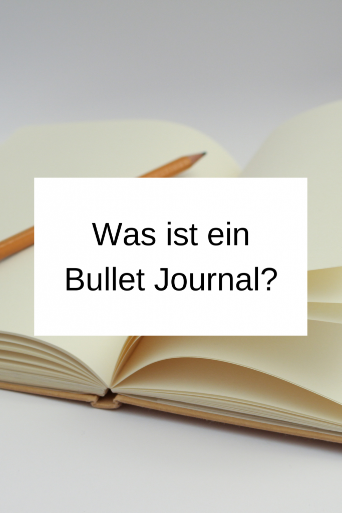 Pinterest-Pin: Was ist ein Bullet Journal? Im Hintergrund ist ein aufgeschlagenes Notizbuch zu sehen. 