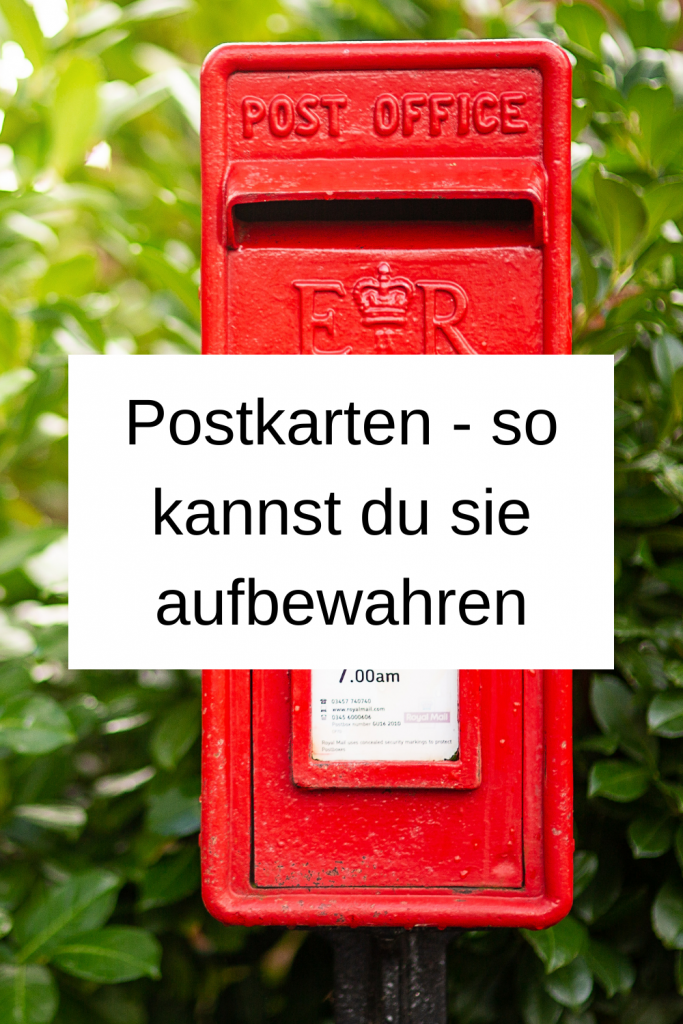 Pinterest-Pin: Postkarten - so kannst du sie aufbewahren. Im Hintergrund ist ein roter Briefkasten vor einer grünen Hecke zu sehen. 